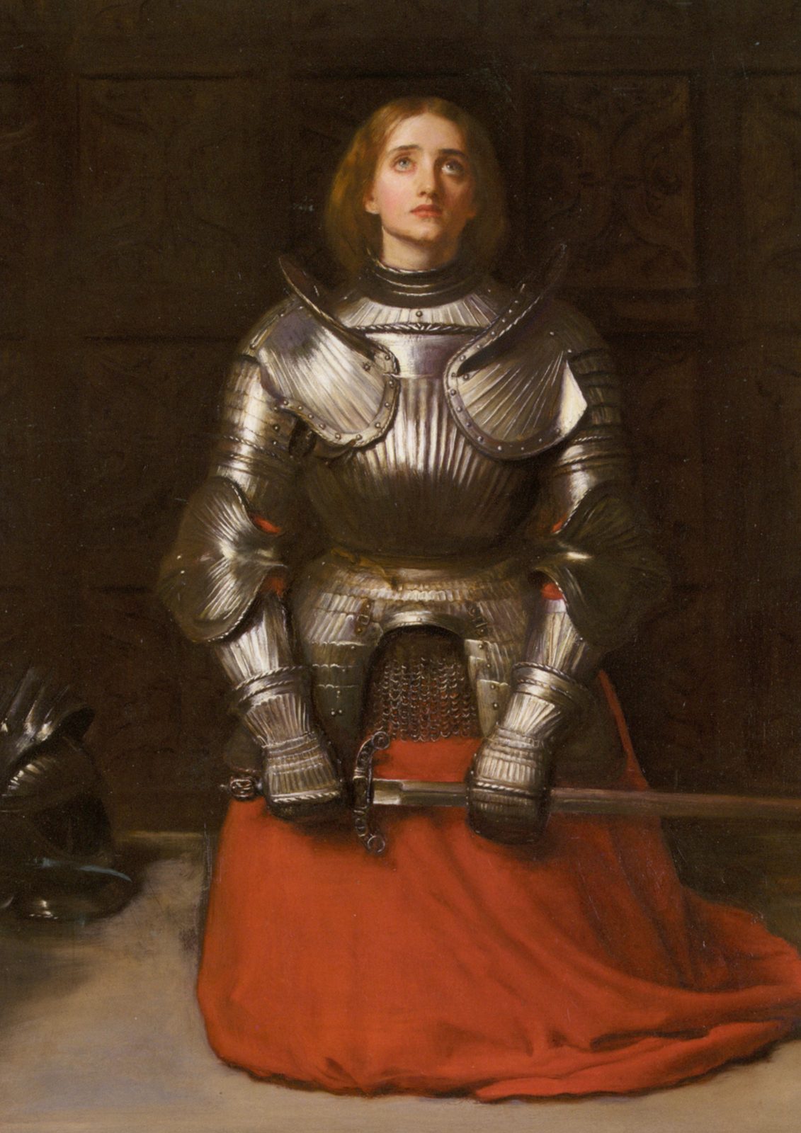 Joan of Arc by John Everett Millais, 1865. A young woman in plate armour kneels in prayer, her hands clasped around the hilt of a sword, her eyes raised.